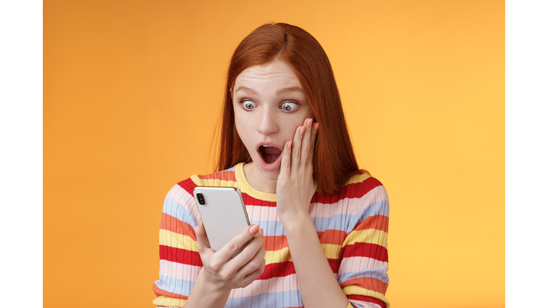 Portrait Of Beautiful Young Woman Using Smart Phone Against Orange Background