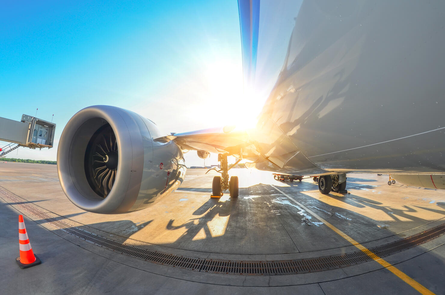 Bright sun over the wing and engine of an airplane at the airport.
