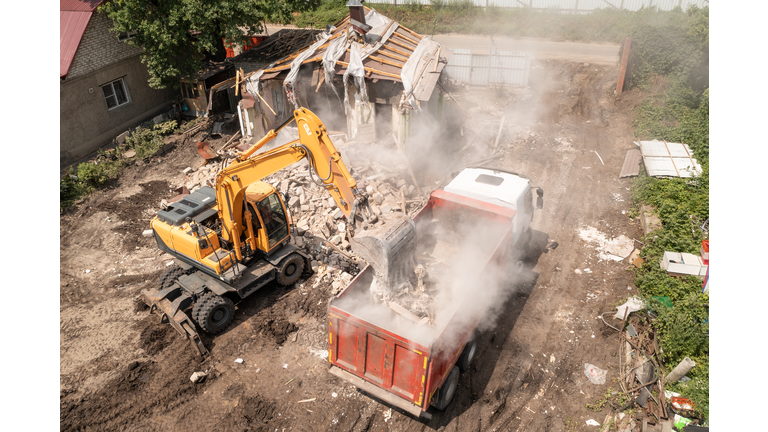 Demolition Of House Building For New Construction. Excavator Bucket Load Garbage into Truck, Aerial View