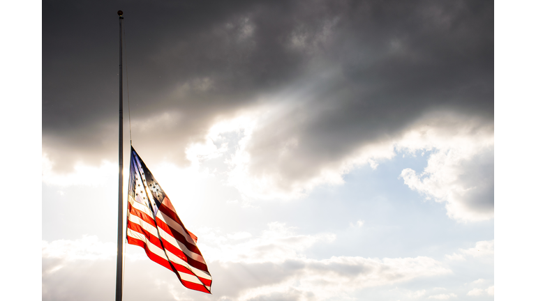 Perfect American Flag lowered to Half-Mast waving in the wind fully extended after another sad memorial