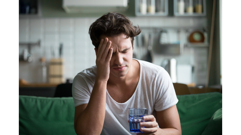 Young man suffering from headache, migraine or hangover at home
