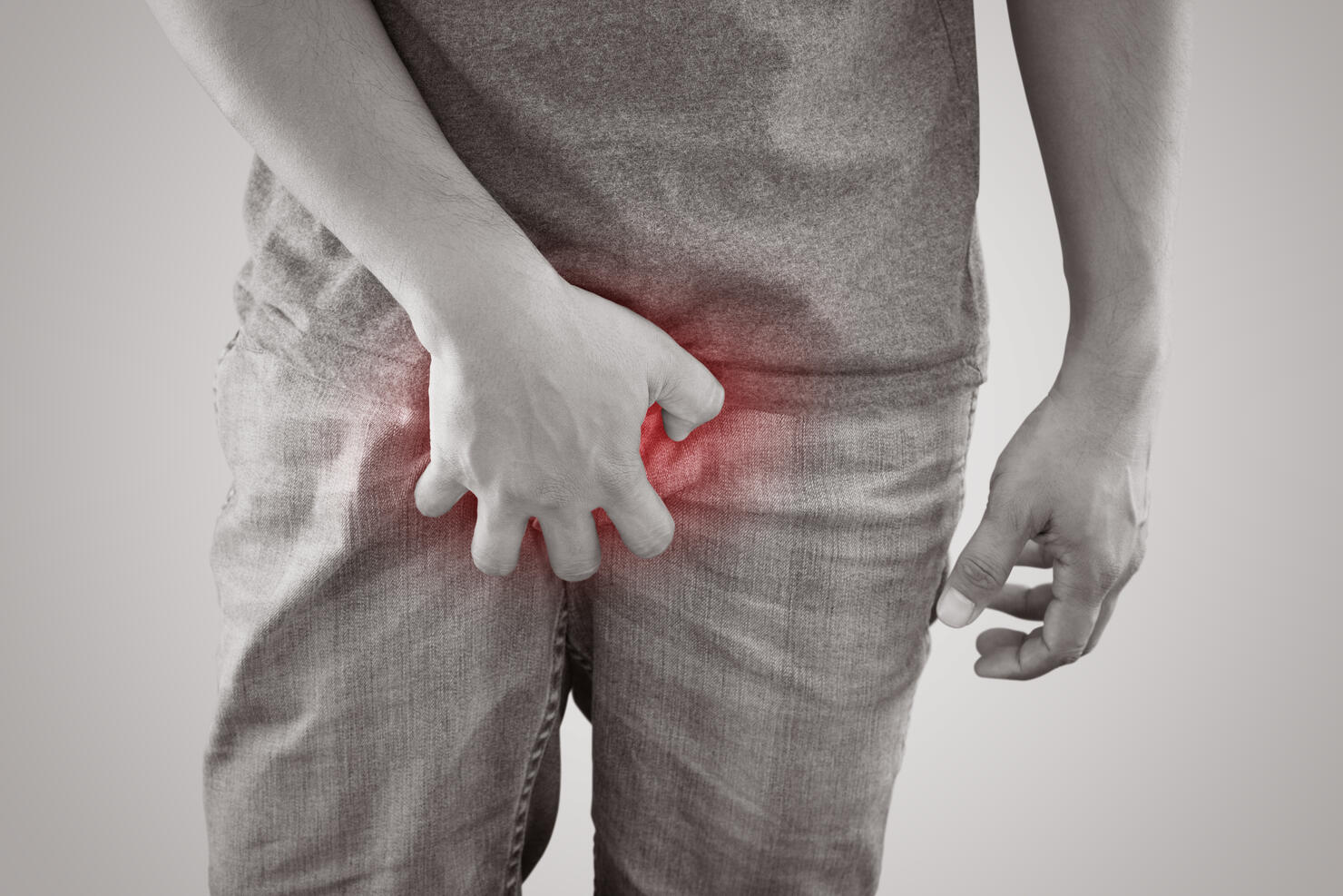 Midsection Of Man Holding Penis While Standing Against White Background