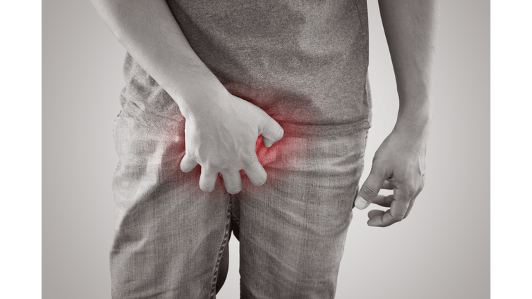 Midsection Of Man Holding Penis While Standing Against White Background