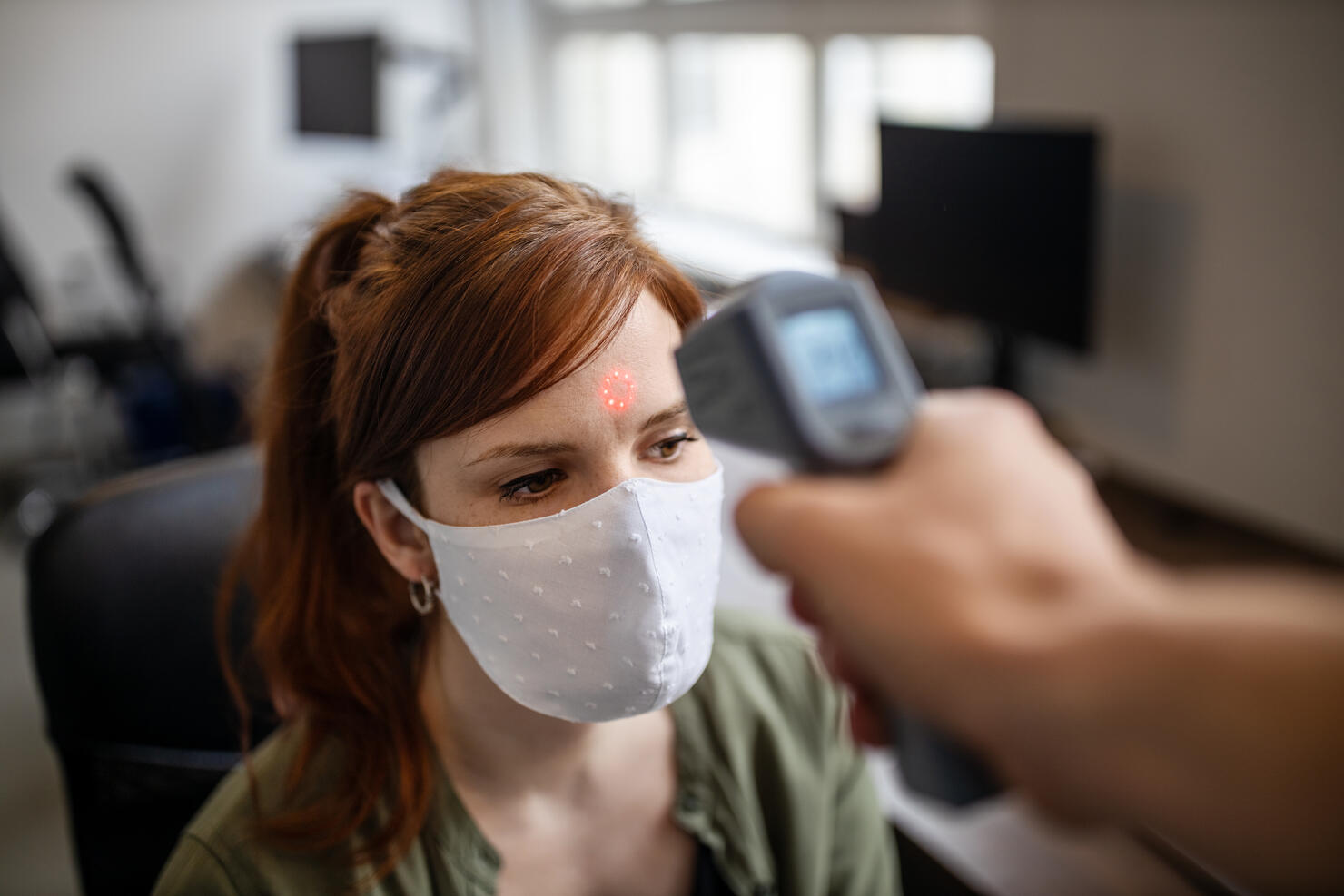 Businesswoman getting her temperature checked in office