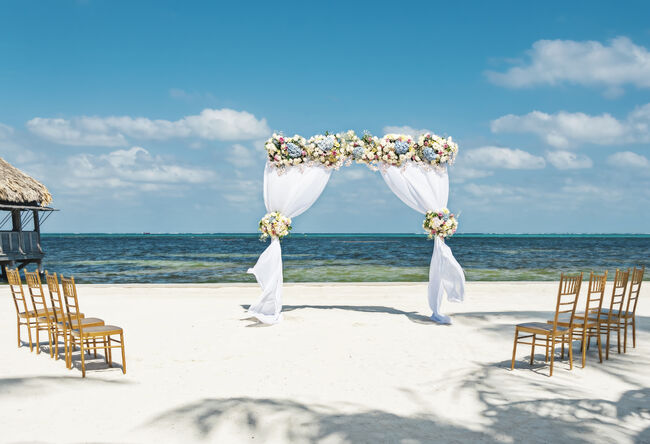 Fresh flower arbor on the beach with eight chairs for a small beach wedding