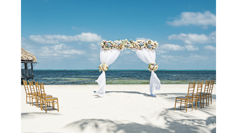 Fresh flower arbor on the beach with eight chairs for a small beach wedding