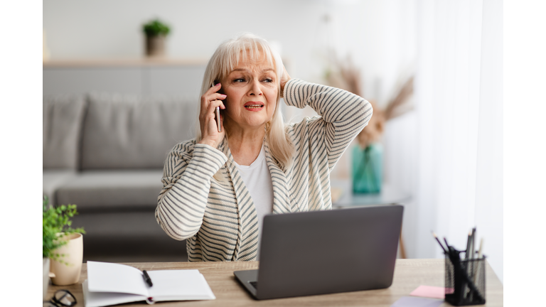 Surprised shocked senior woman talking on mobile phone