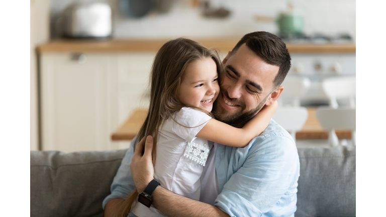 Close up smiling loving young father hugging adorable little daughter