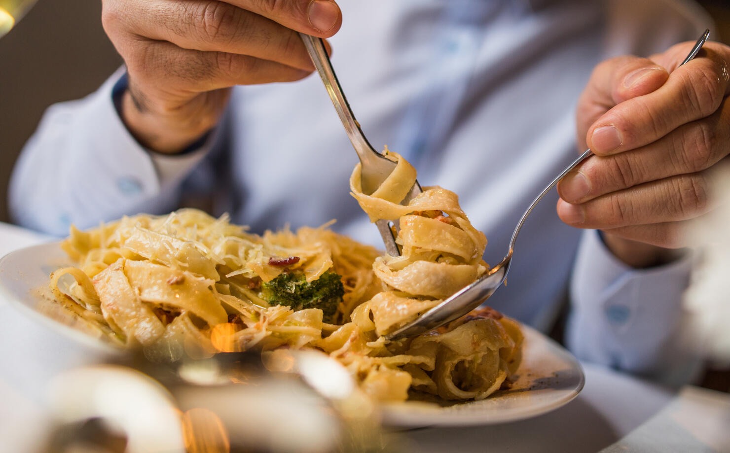 Close up of unrecognizable man eating pasta for lunch.