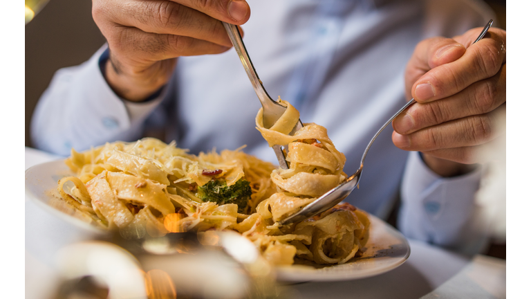 Close up of unrecognizable man eating pasta for lunch.