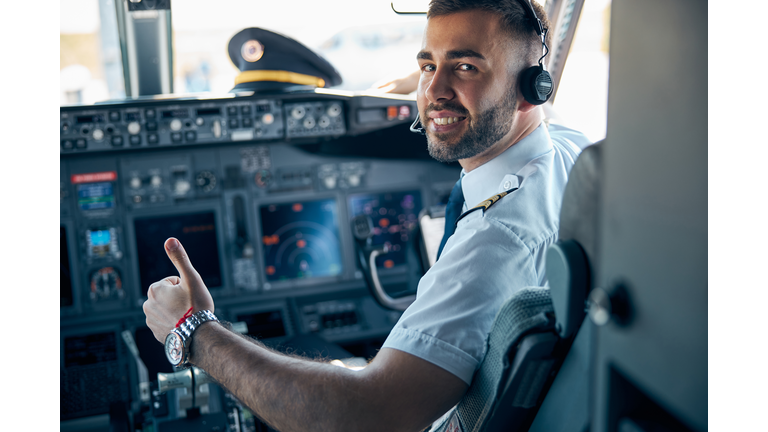 Handsome male posing at the camera in cabin of passenger aircraft