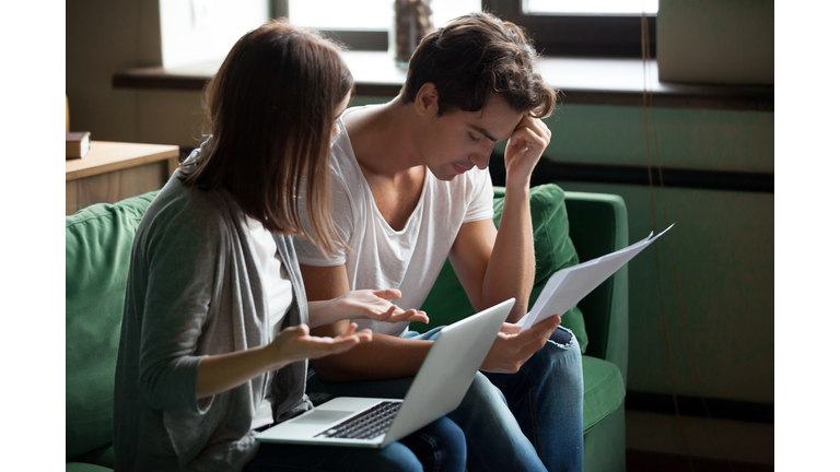 Stressed young couple argue about bills at home