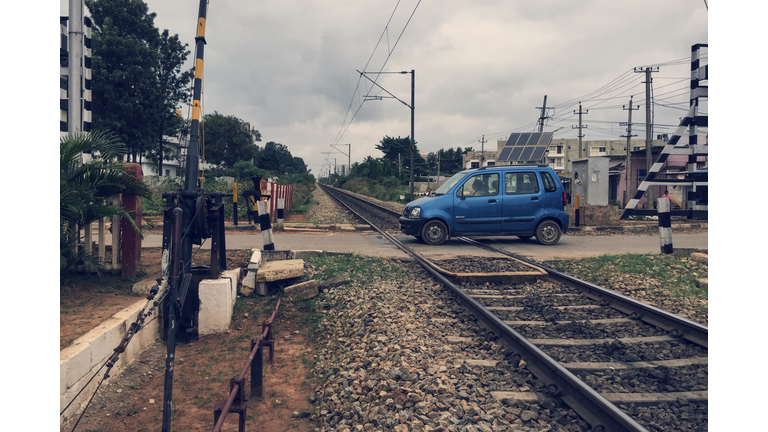 Car On Railroad Crossing Against Cloudy Sky