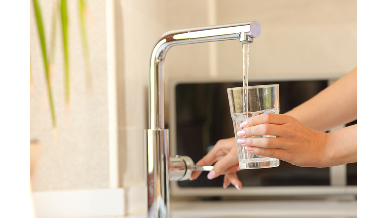 Woman hands filling a glass of tap water