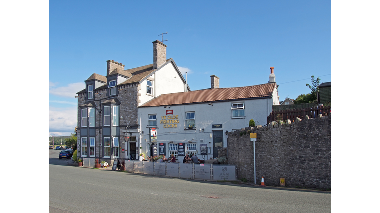 view of the ye olde fighting cocks pub in arnside in cumbria with people drinking outside in summer