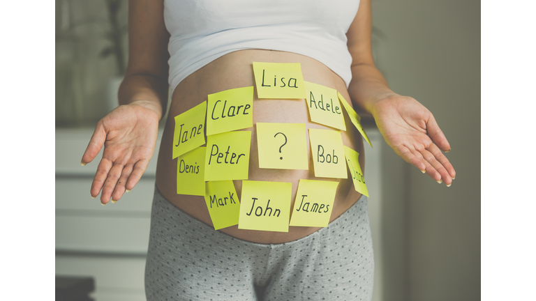 Toned shot of pregnant woman with child names on belly