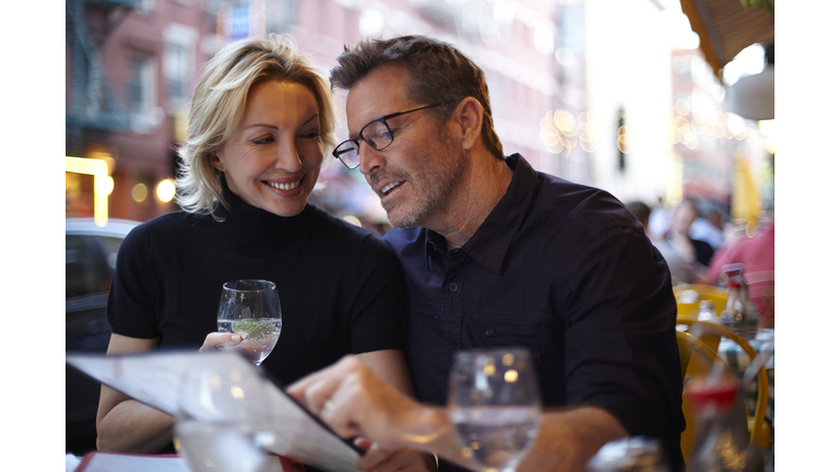 Caucasian couple reading menu at urban cafe, New York City, New York, United States