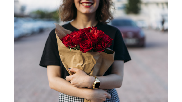 Young woman holding beautiful red flowers bouquet