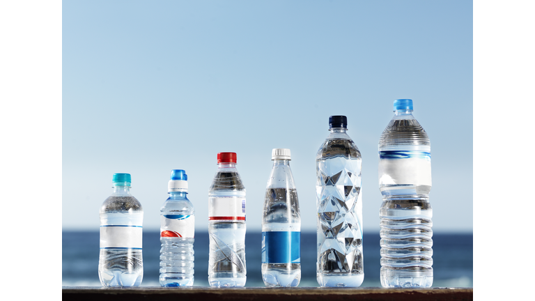 Row of assorted water bottles against the ocean