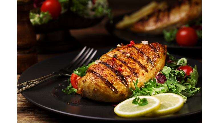grilled chicken breast with green salad and french fries.