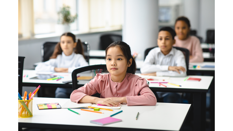 Portrait of focused asian girl sitting at desk in classroom