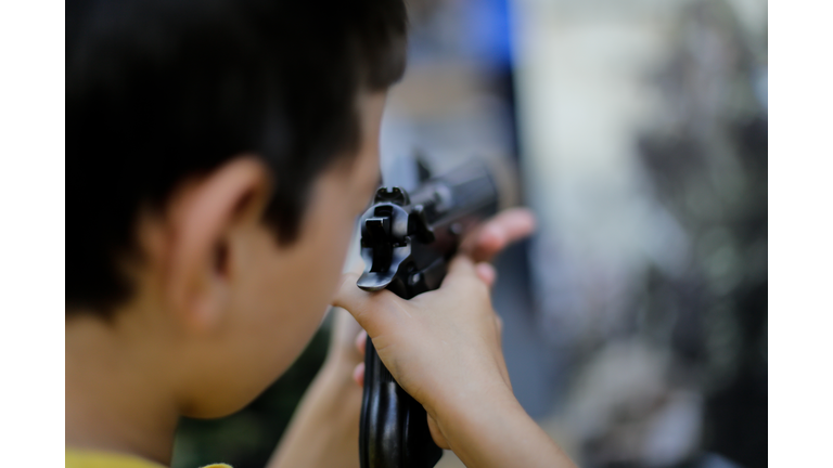 A boy aims a 9 mm pistol
