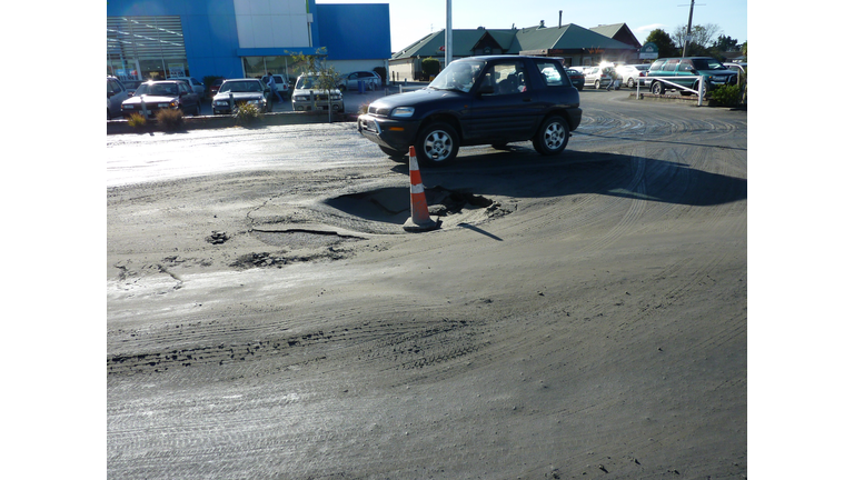 A car drives past a sink hole, caused by