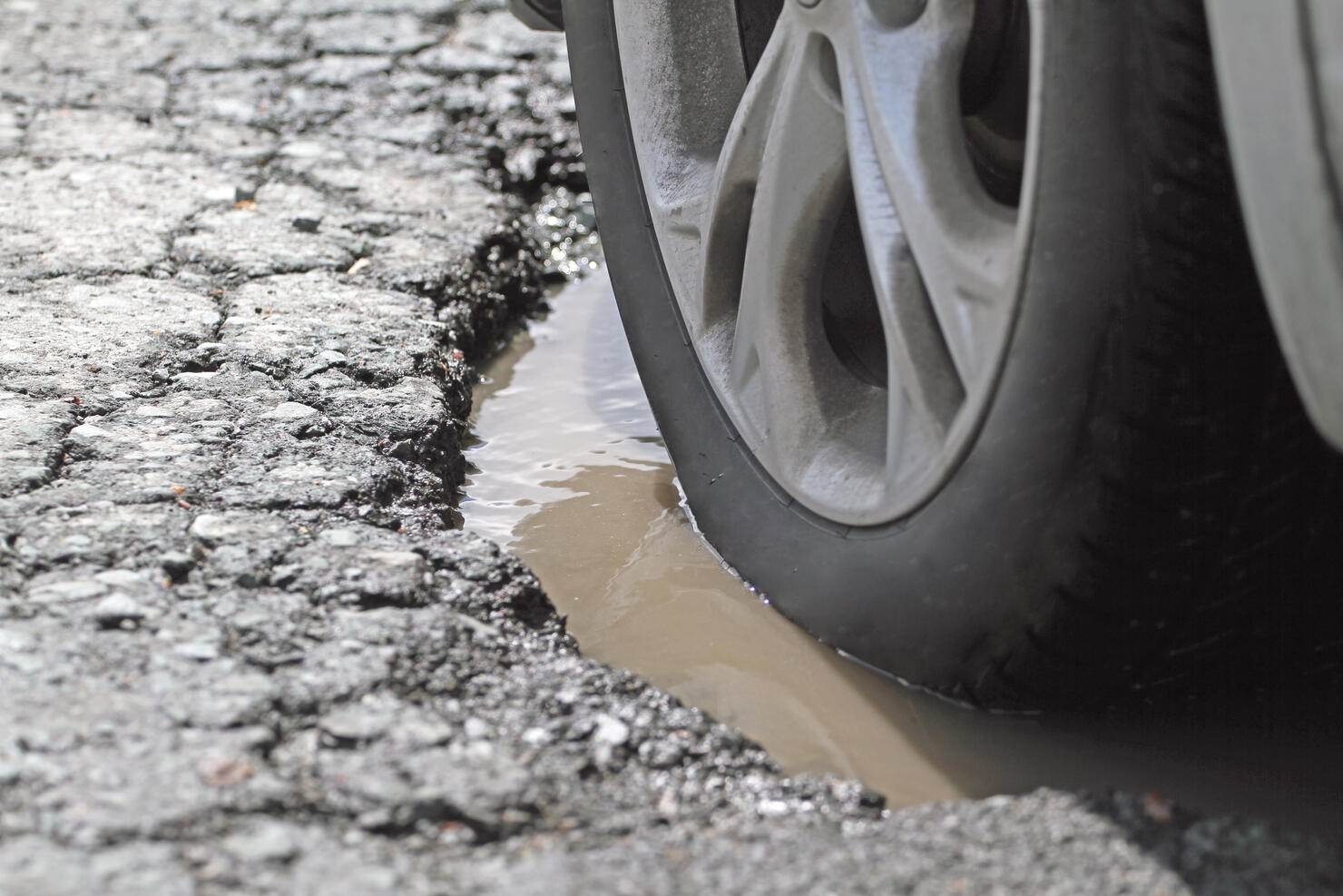 Alloy Wheel And Tire In A Pothole, Closeup