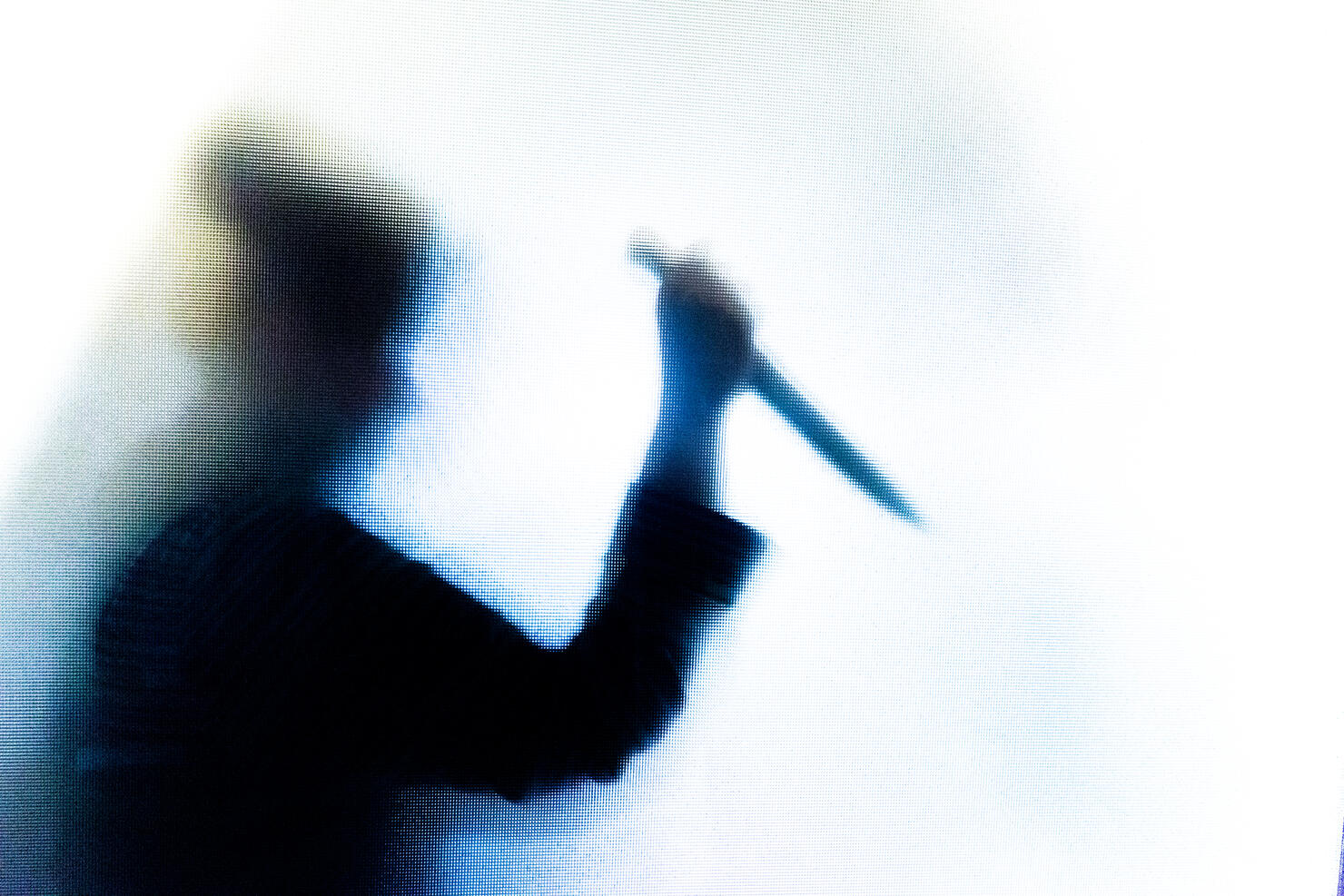 Violent silhouette of person wielding a knife behind frosted glass window