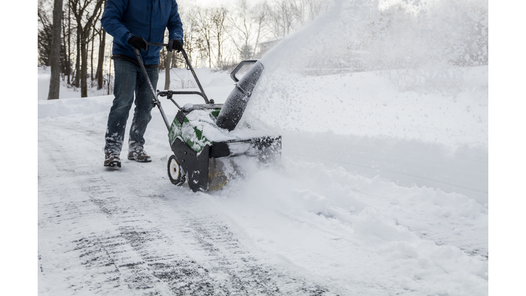 Snow blower in action clearing a residential driveway after snow storm