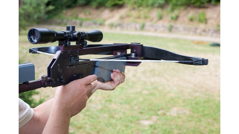 Man holding a scoped crossbow
