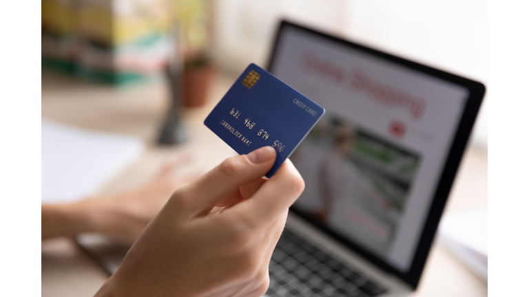 Close up woman holding plastic credit card, using laptop