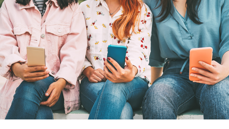 Happy Asian friends using mobile smart phone outdoor - Millennial young people addicted to new technologies trends and social media network - Concept of generation z, tech and youth lifestyle