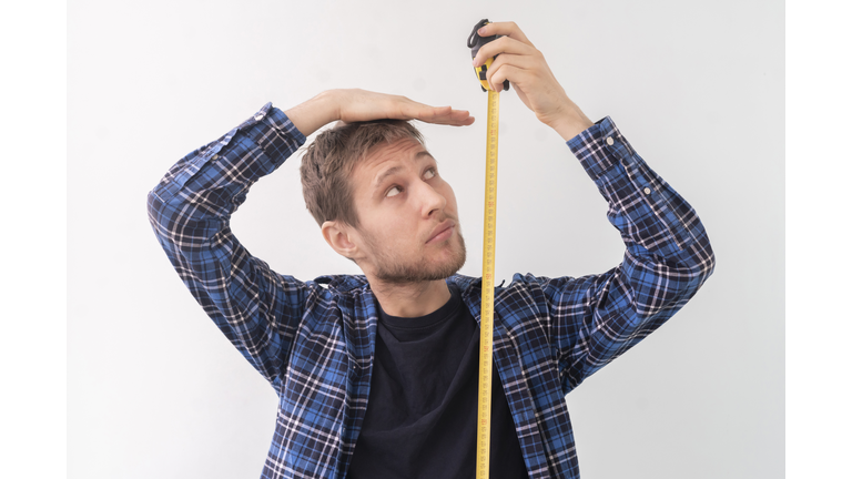 simple adult teenager male person with a roll tape measure the height against the wall