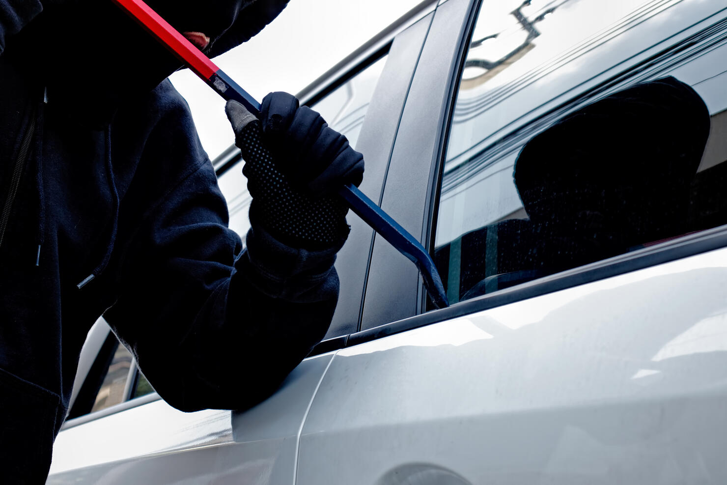 Masked burglar trying to get into a car