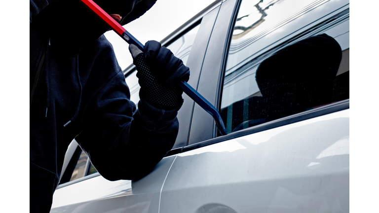 Masked burglar trying to get into a car