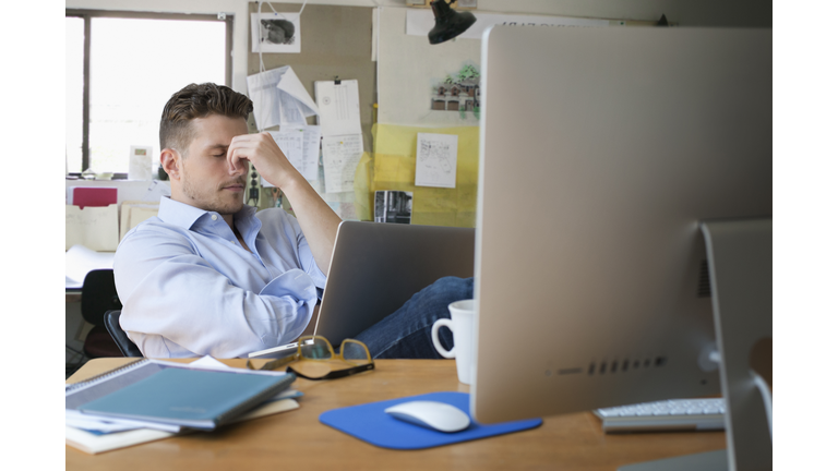 Frustrated Caucasian businessman with laptop in office