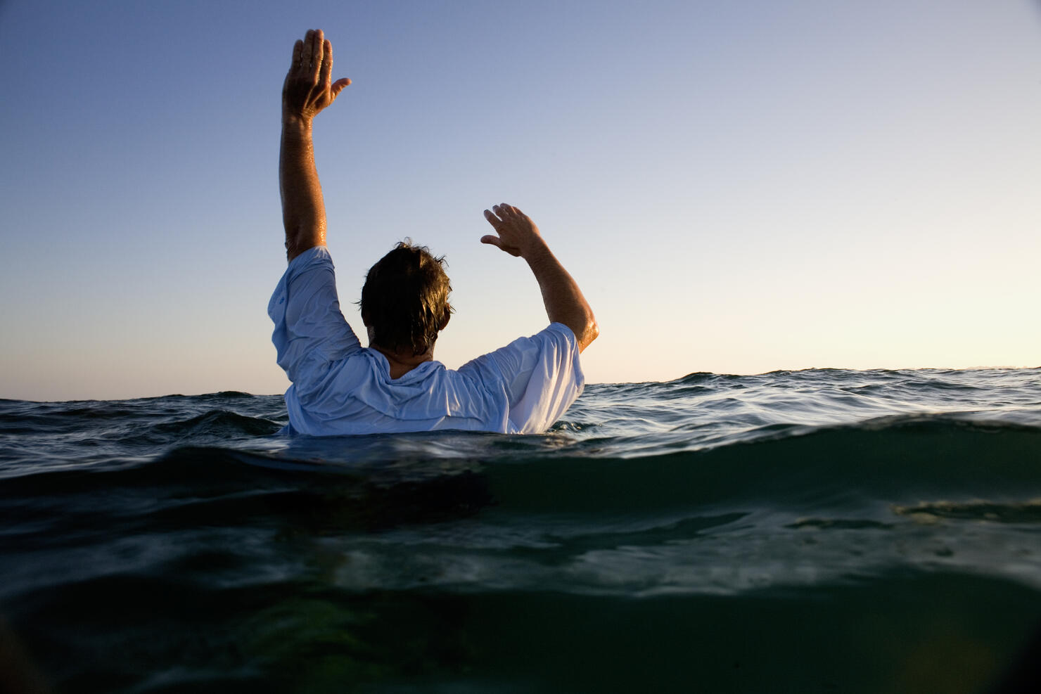 Man overboard in sea waving for help, rear view