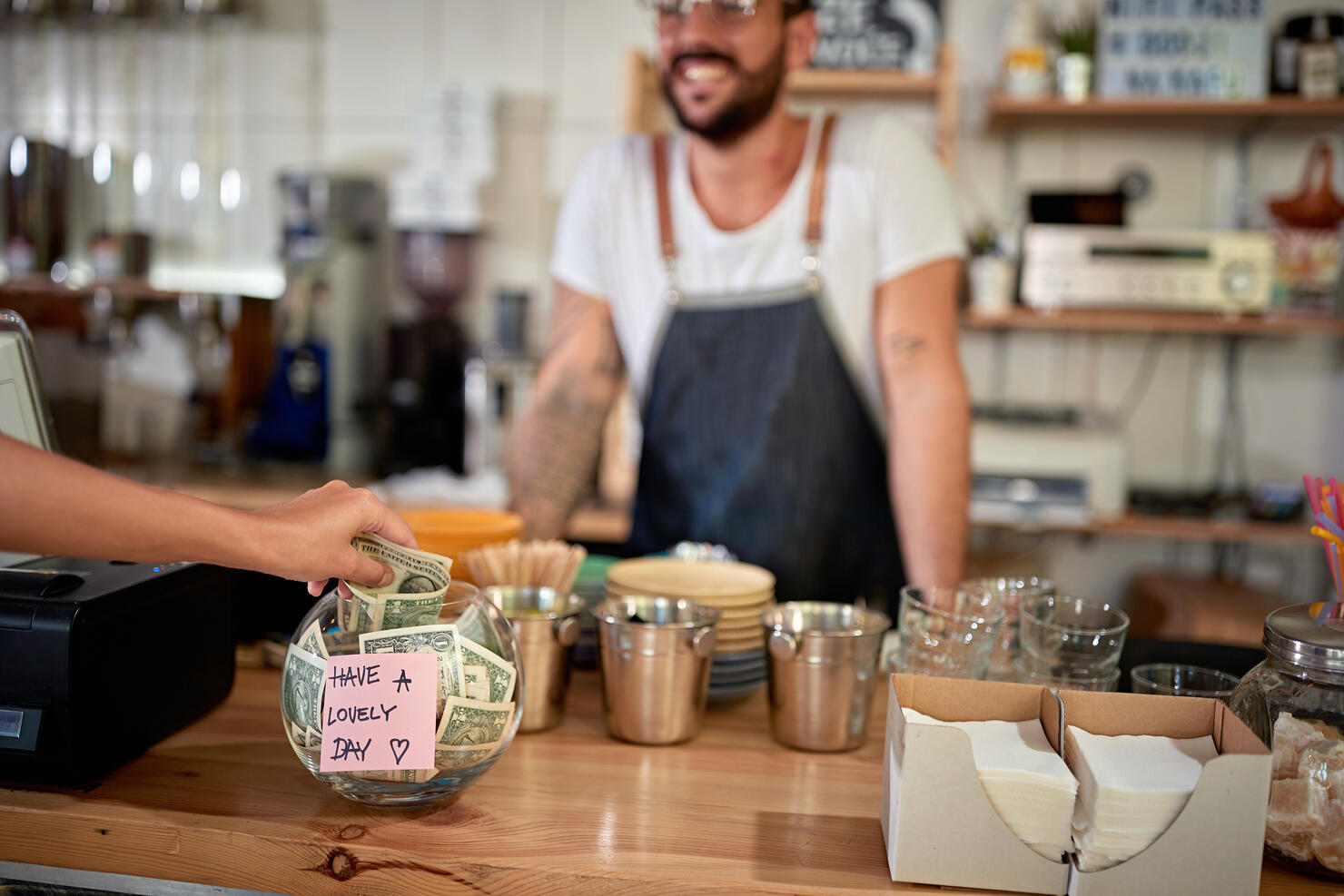 satisfied customer leaving tip in a bowl with a positive message on a sticker. money, tip, satisfied, positive message