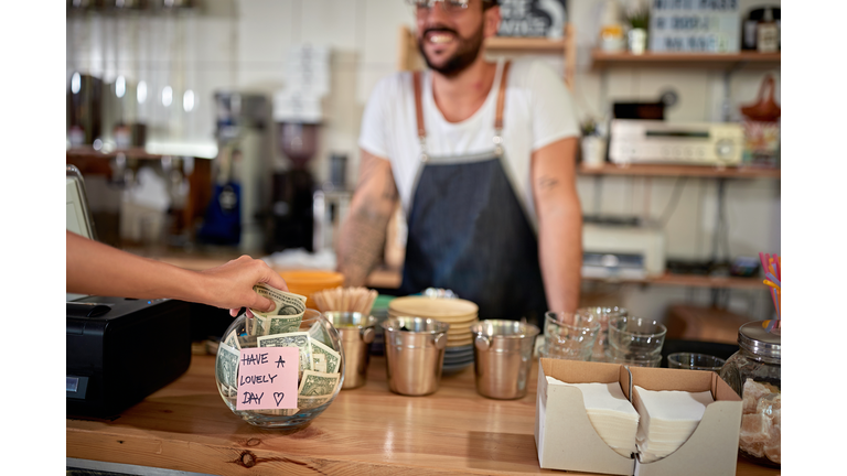 satisfied customer leaving tip in a bowl with a positive message on a sticker. money, tip, satisfied, positive message