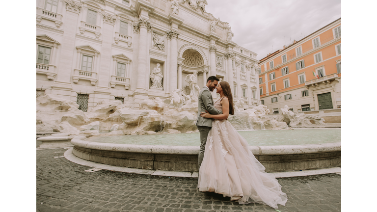 Bride and groom posing in front of Trevi Fountain (Fontana di Trevi), Rome, Italy