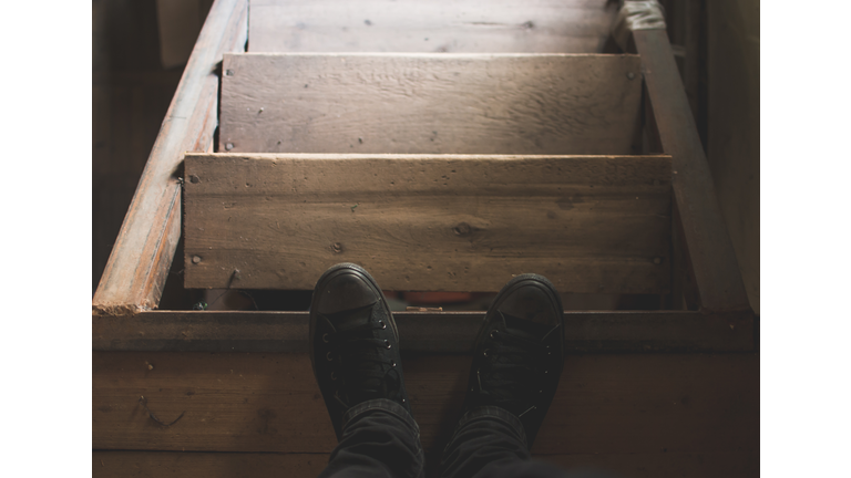Man's black sneakers and old dusty loft wooden stairs