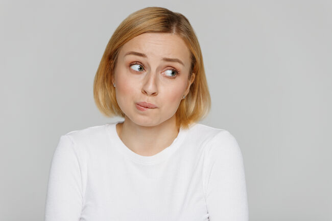 shy awkward young woman biting lips feeling embarrassed, confused, nervous