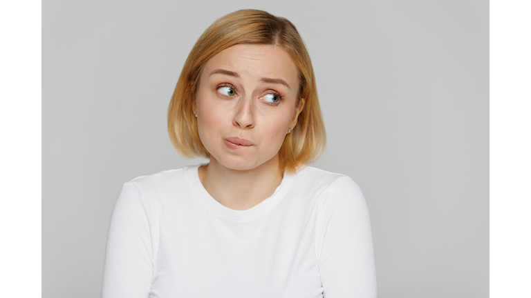 shy awkward young woman biting lips feeling embarrassed, confused, nervous