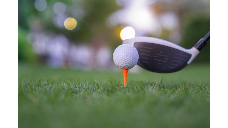 Golf ball on green grass ready to be struck on golf course backgroun