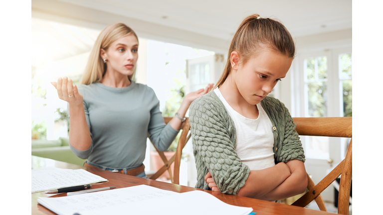 Shot of a young mother looking frustrated while helping her daughter with homework at home