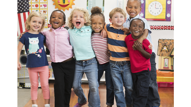 Portrait of smiling students hugging in classroom