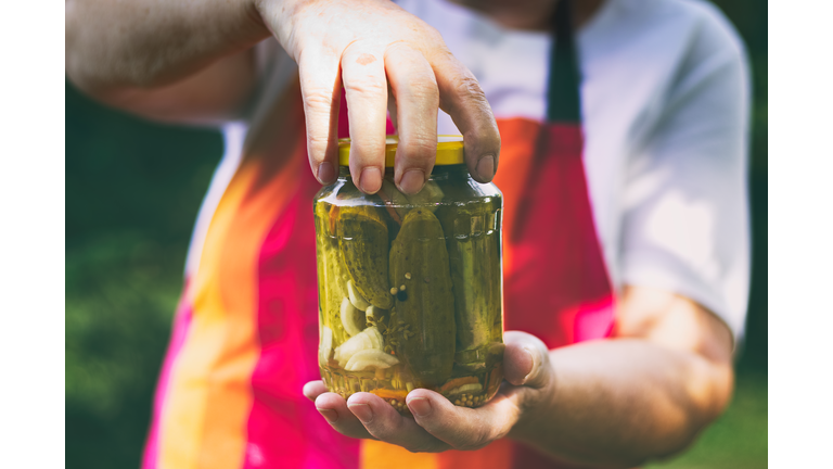 Senior woman holding a jar of pickles in the garden