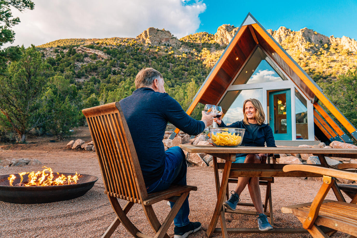 "Cheers!" Caucasian Couple Sharing a Celebratory Toast with Local Wine, Chips, and Salsa Together in a Xeriscaped Yard with a Cute Modern Xeriscaped Tiny Home in the Background