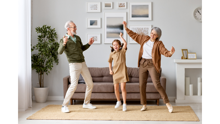 Excited preschool girl having fun with active positive grandpare